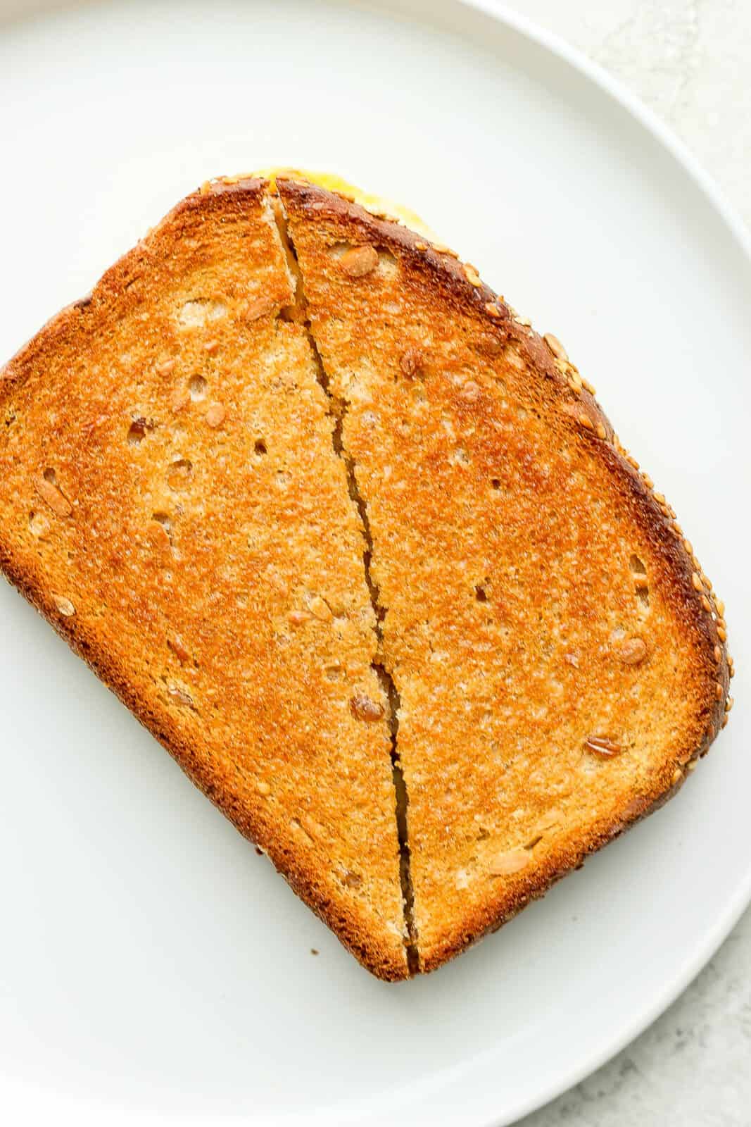 A perfectly browned air fryer grilled cheese cut in half on a plate.
