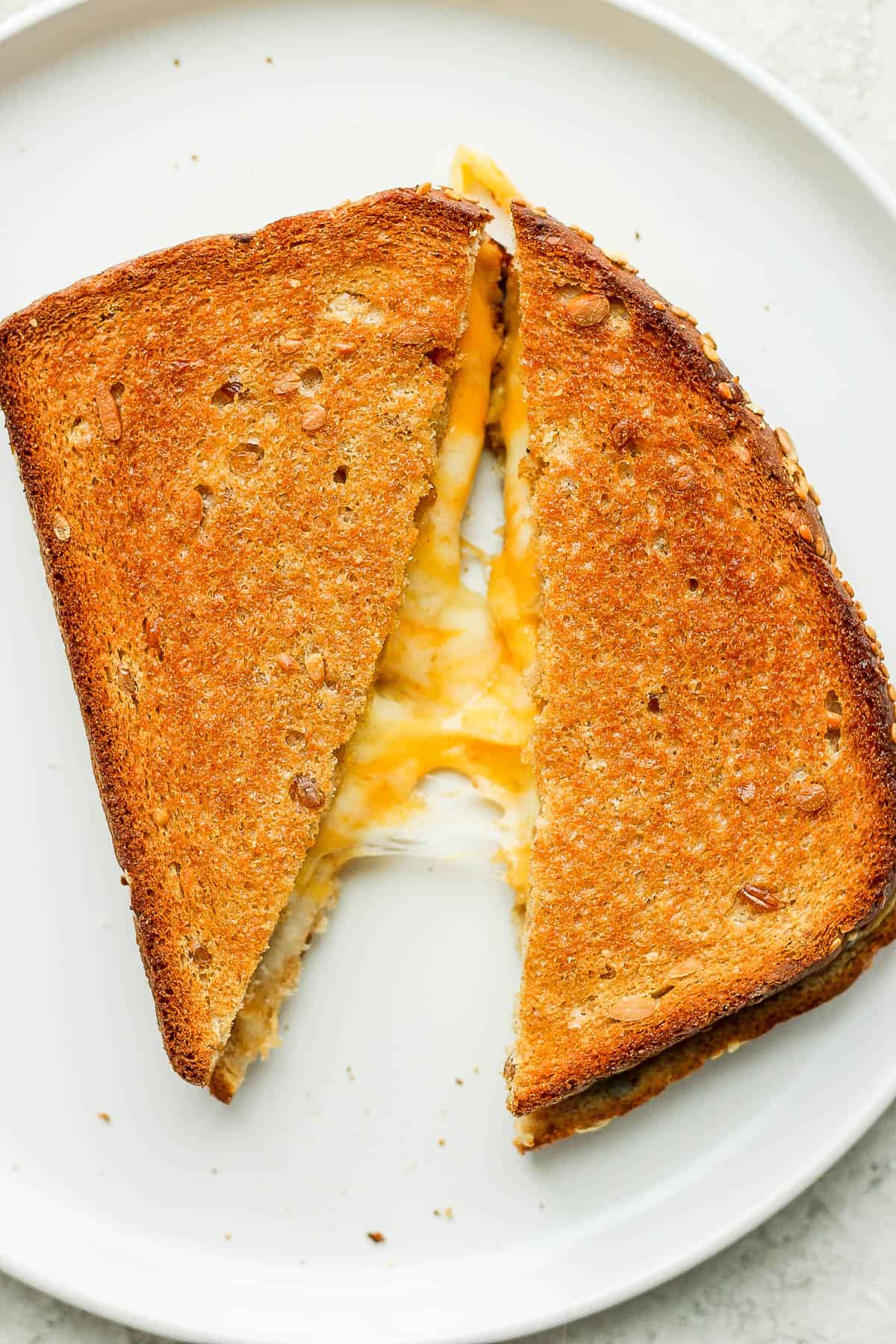 A grilled cheese sandwich that has been cut in half on a white plate.