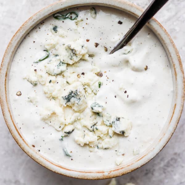 A small bowl of homemade blue cheese dressing with the a spoon sticking out.