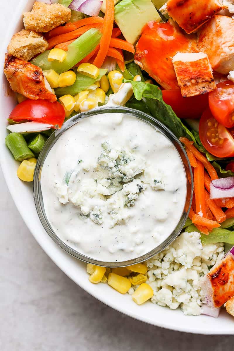 A small dish of blue cheese dressing in a salad.