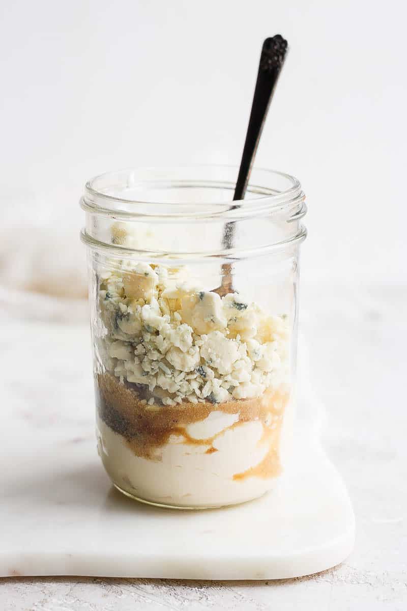 Blue cheese dressing ingredients in a mason jar with a spoon.
