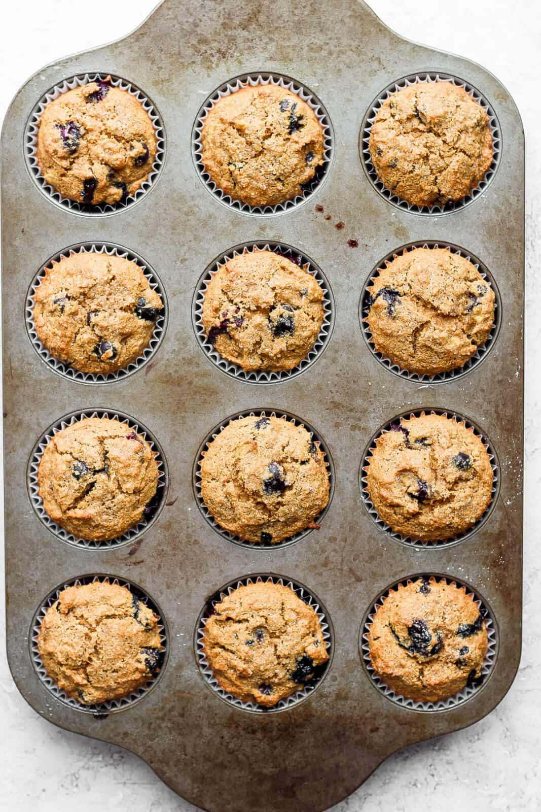 Fully baked blueberry banana muffins in a muffin tin.