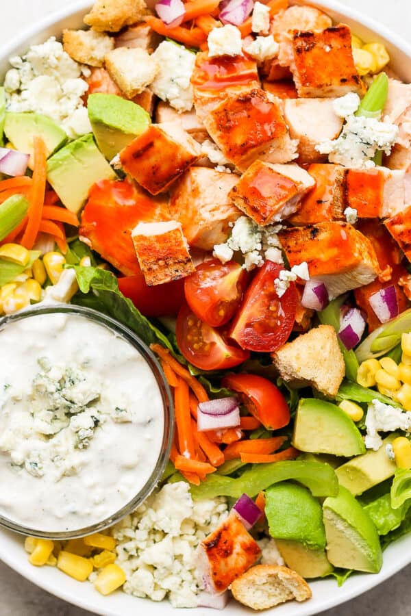 Big bowl of buffalo chicken salad with a cup of blue cheese dressing.