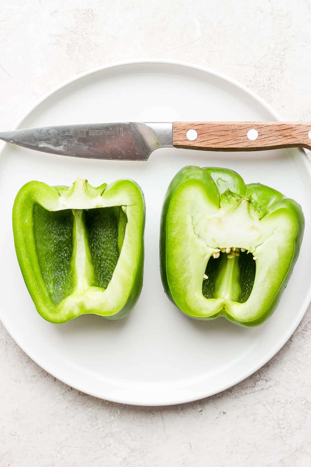 A green bell pepper cut in half on a plate.