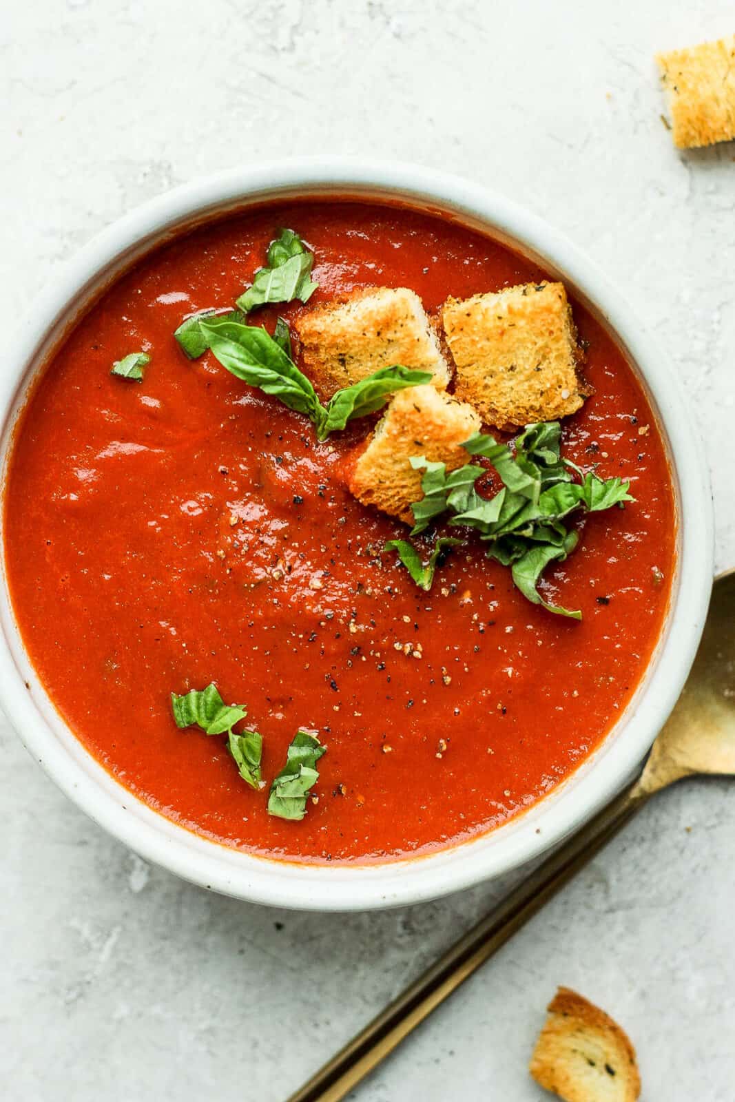 Homemade croutons on top of a bowl of tomato basil soup.