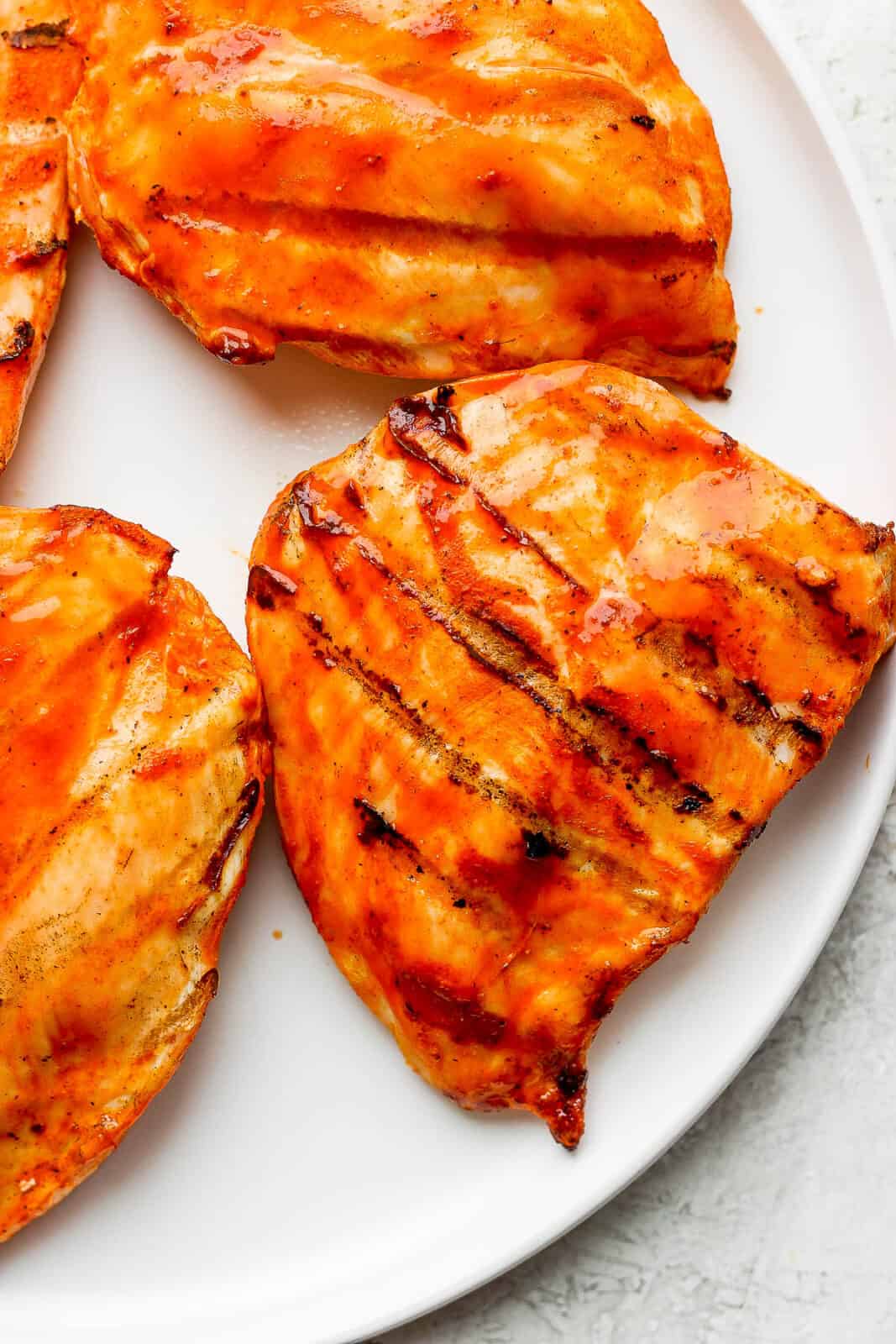 Grilled buffalo chicken breasts on a plate.