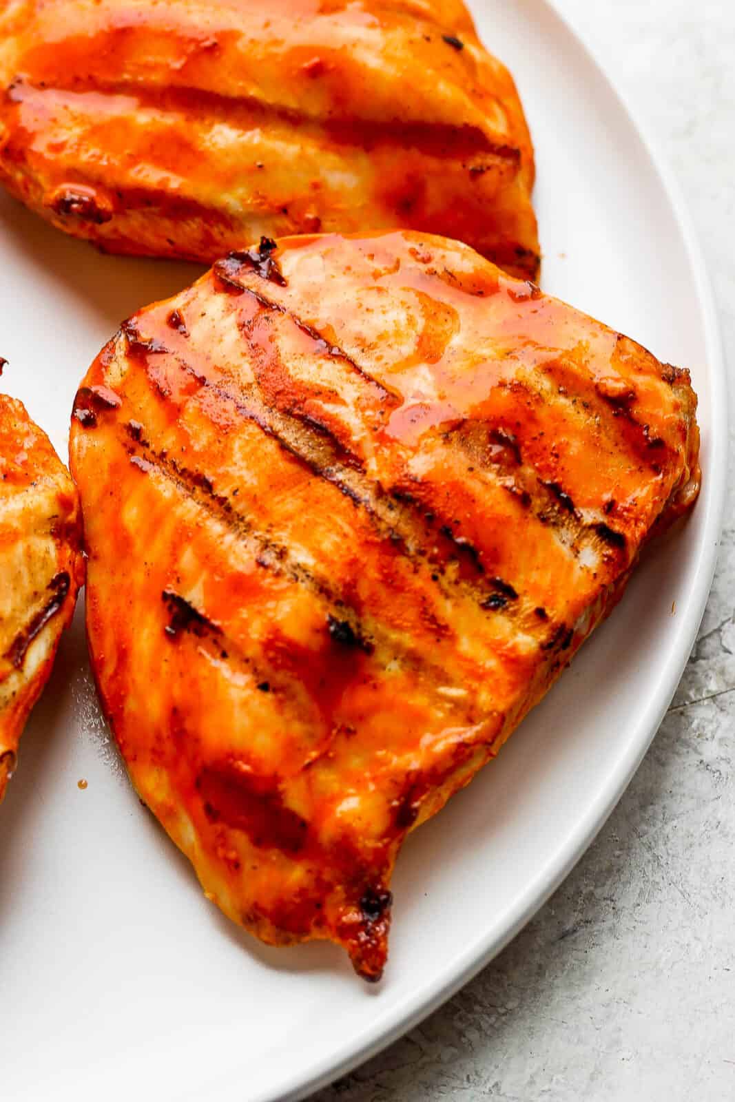 Grilled buffalo chicken breasts on a plate.