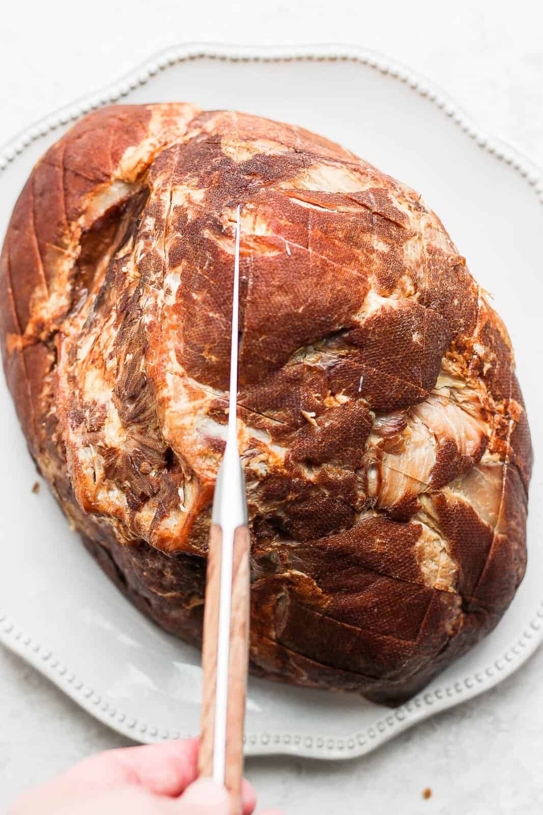 Someone scoring the outer part of a ham. 