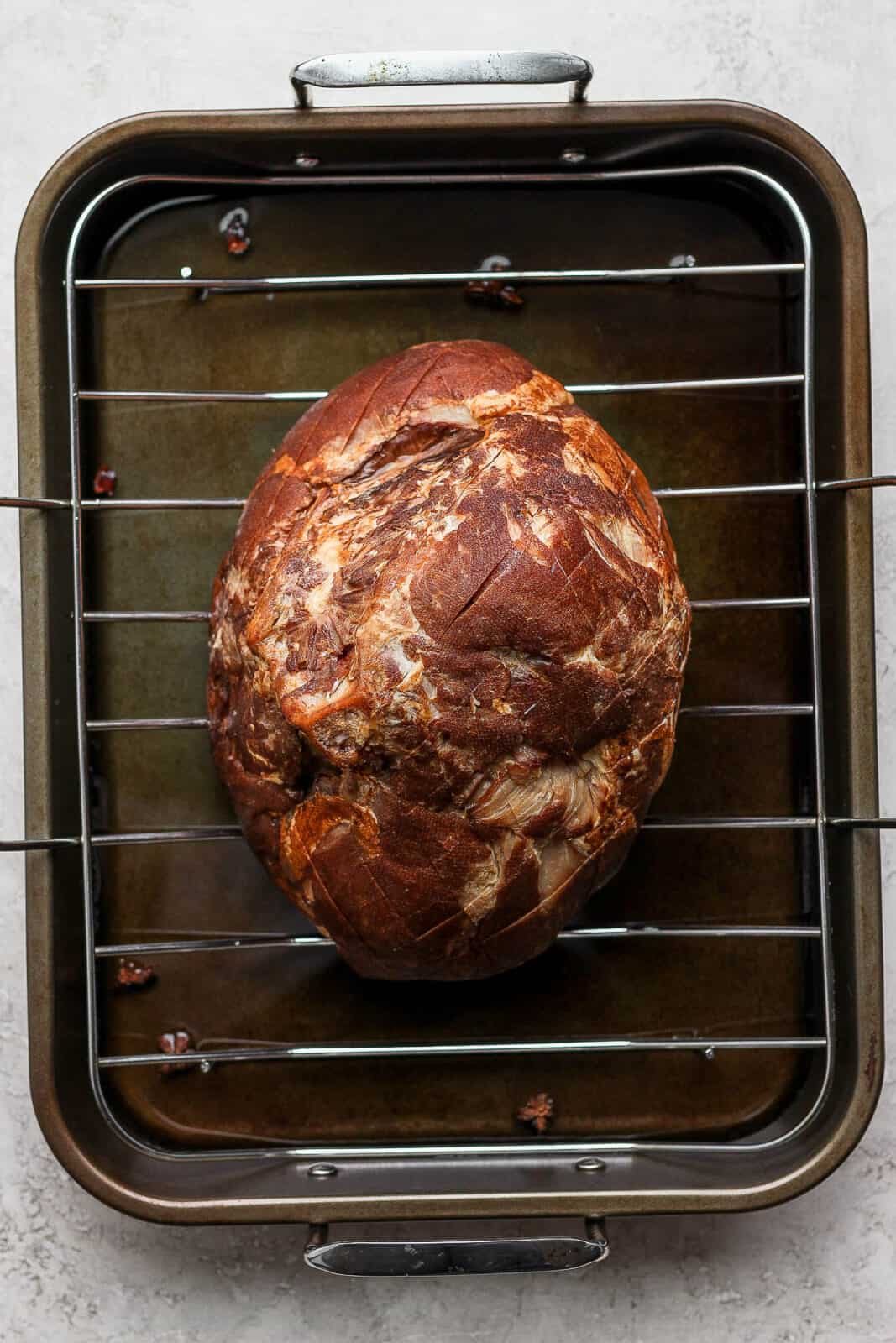 A scored ham sitting in a roaster before cooking. 