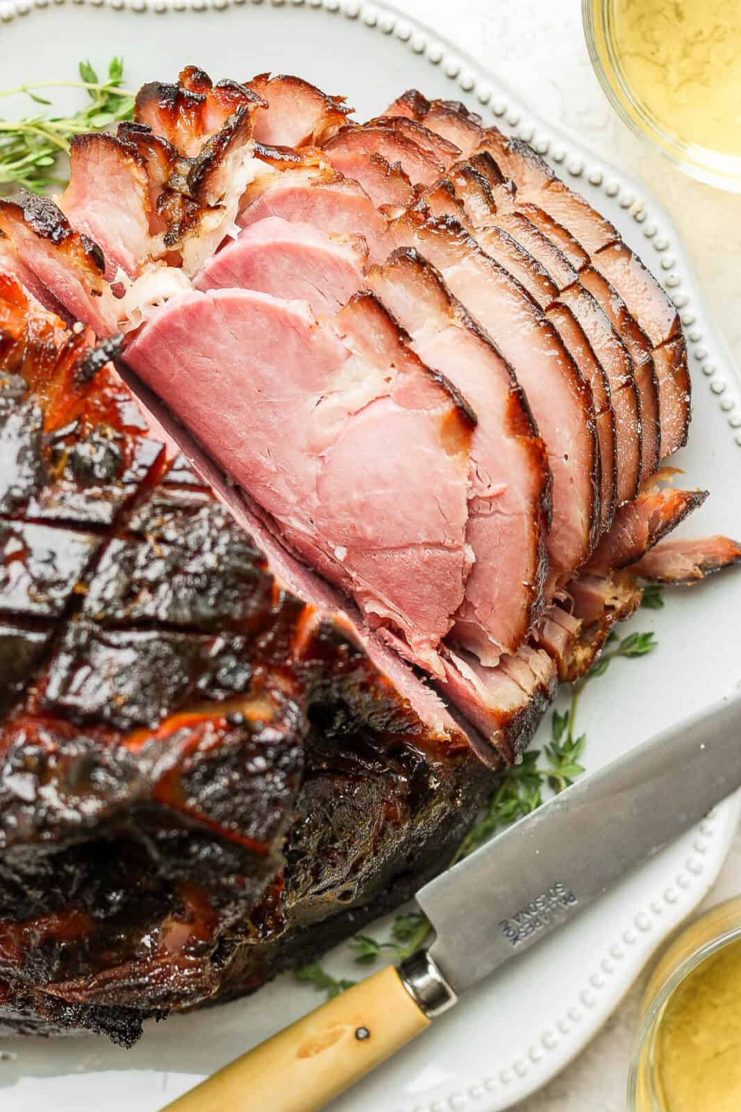 Top shot of a honey glazed ham with half the ham cut into thin slices. 