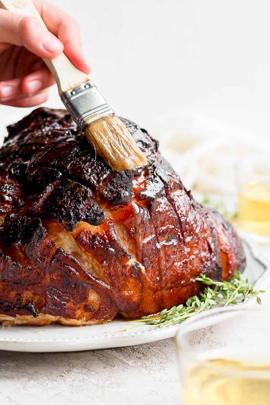 Honey bourbon glaze being basted on a ham.