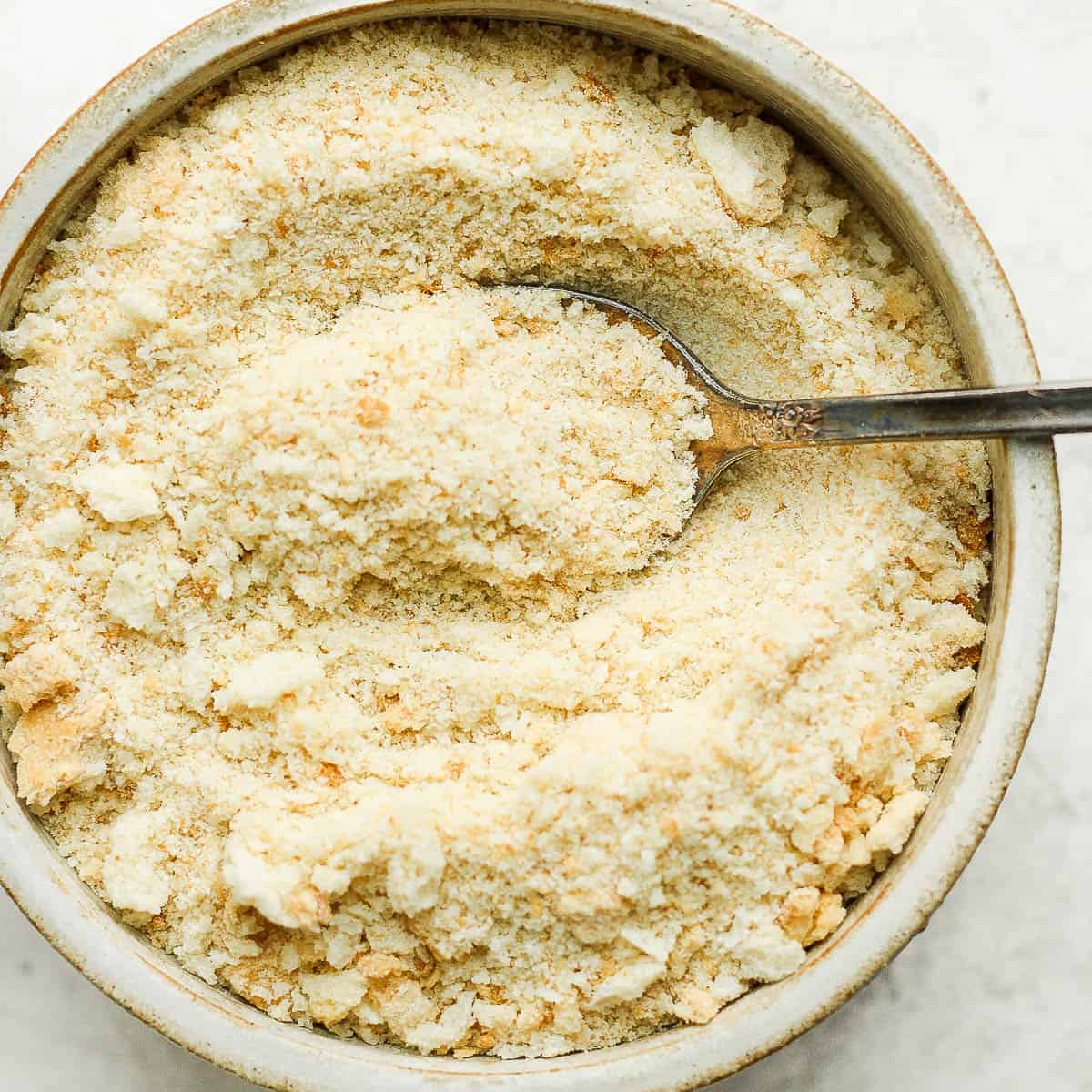 Bowl of homemade bread crumbs with spoon sticking out of it.