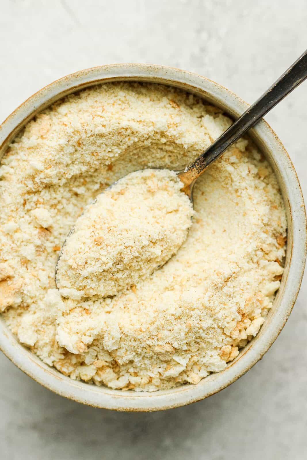 Breadcrumbs in a bowl with a spoon.