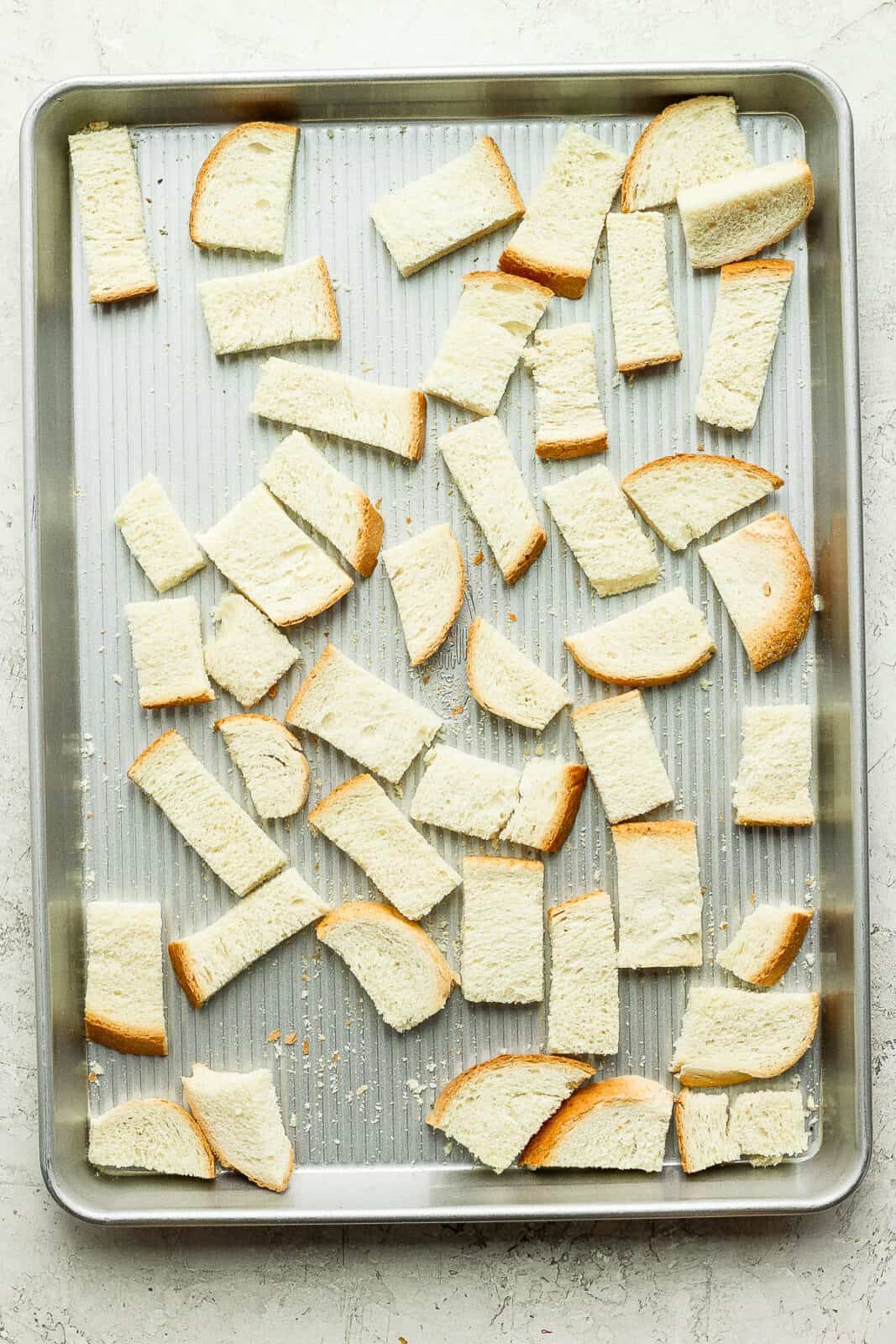 Cubed bread on a baking sheet.