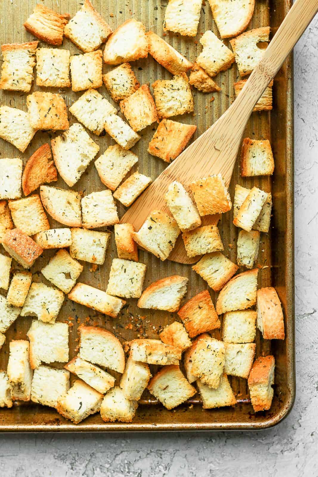 Croutons being scooped up by a wooden spatula.