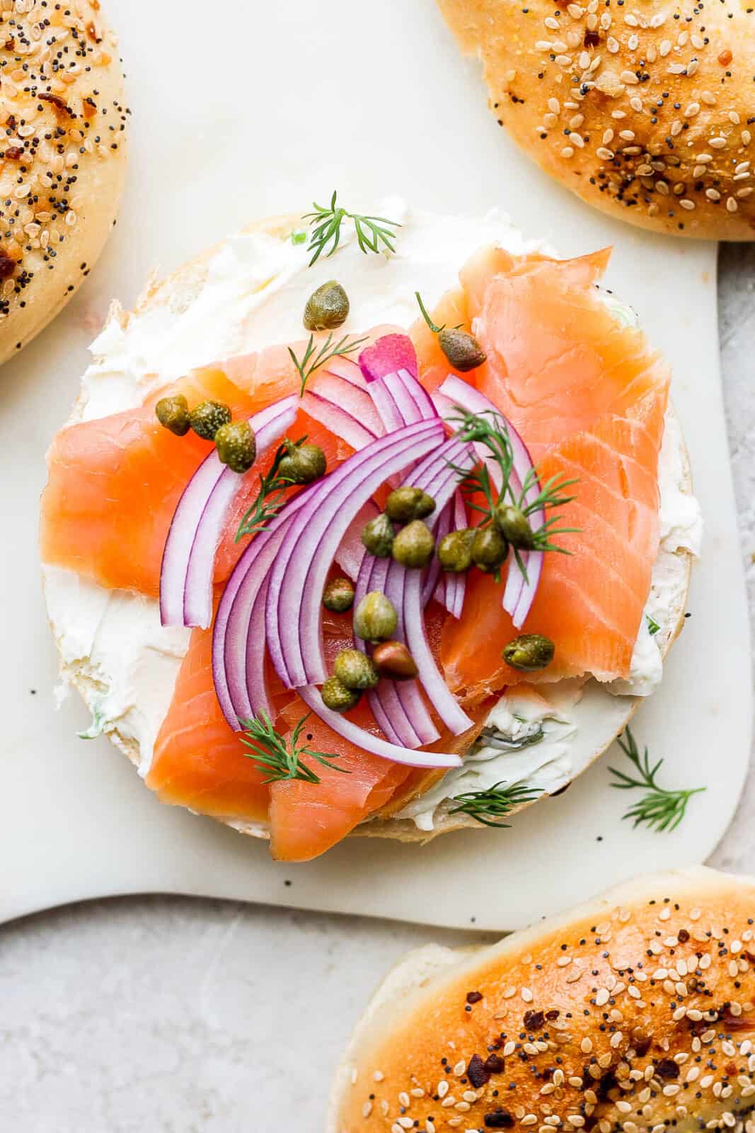 A bagel half with cream cheese, lox, red onion, dill and caper. 