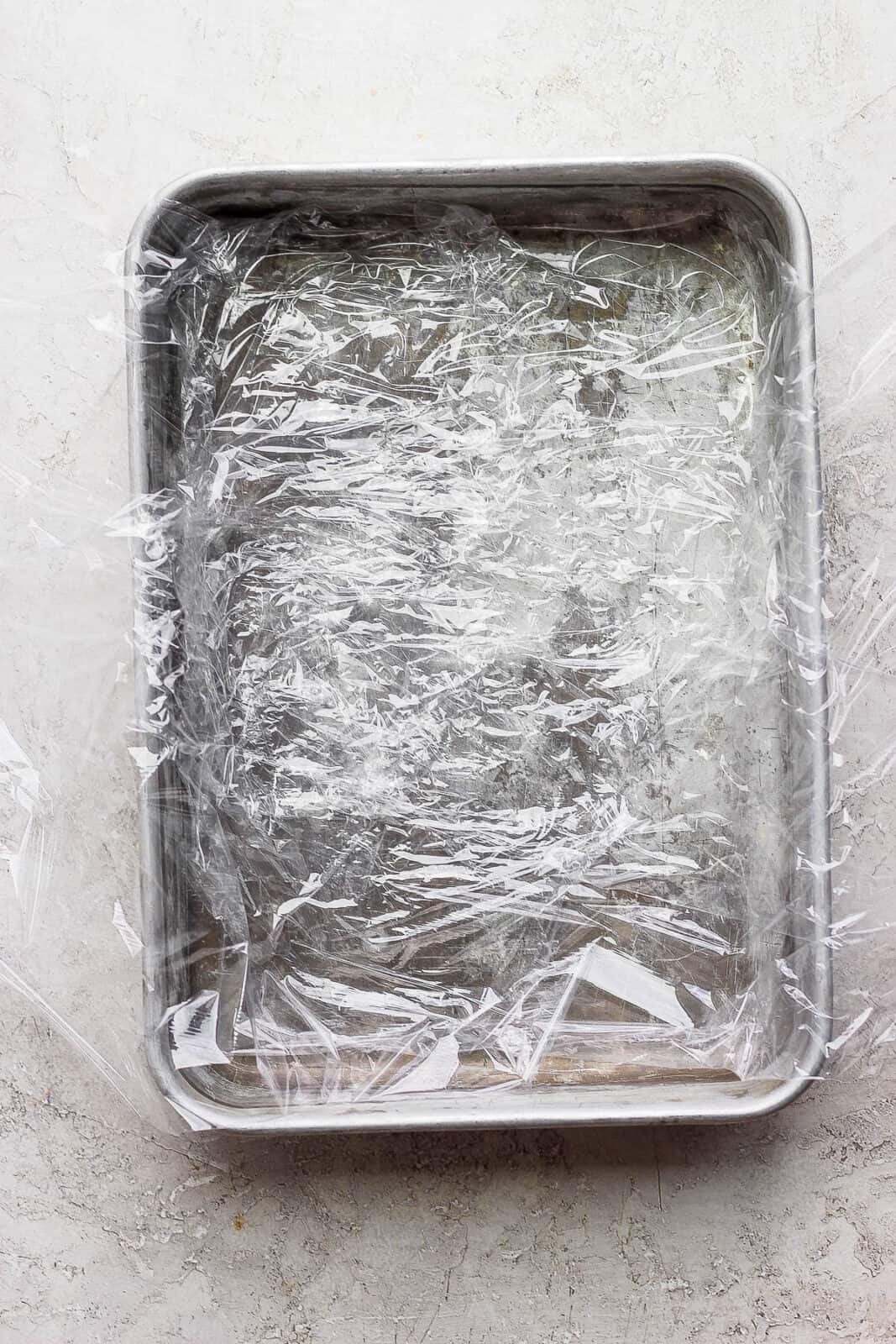 A large baking dish with plastic wrap across it. 