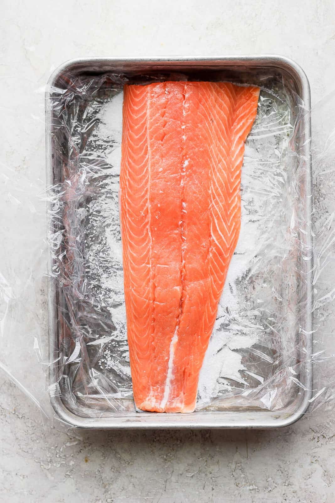 A raw fillet of salmon inside a baking dish.