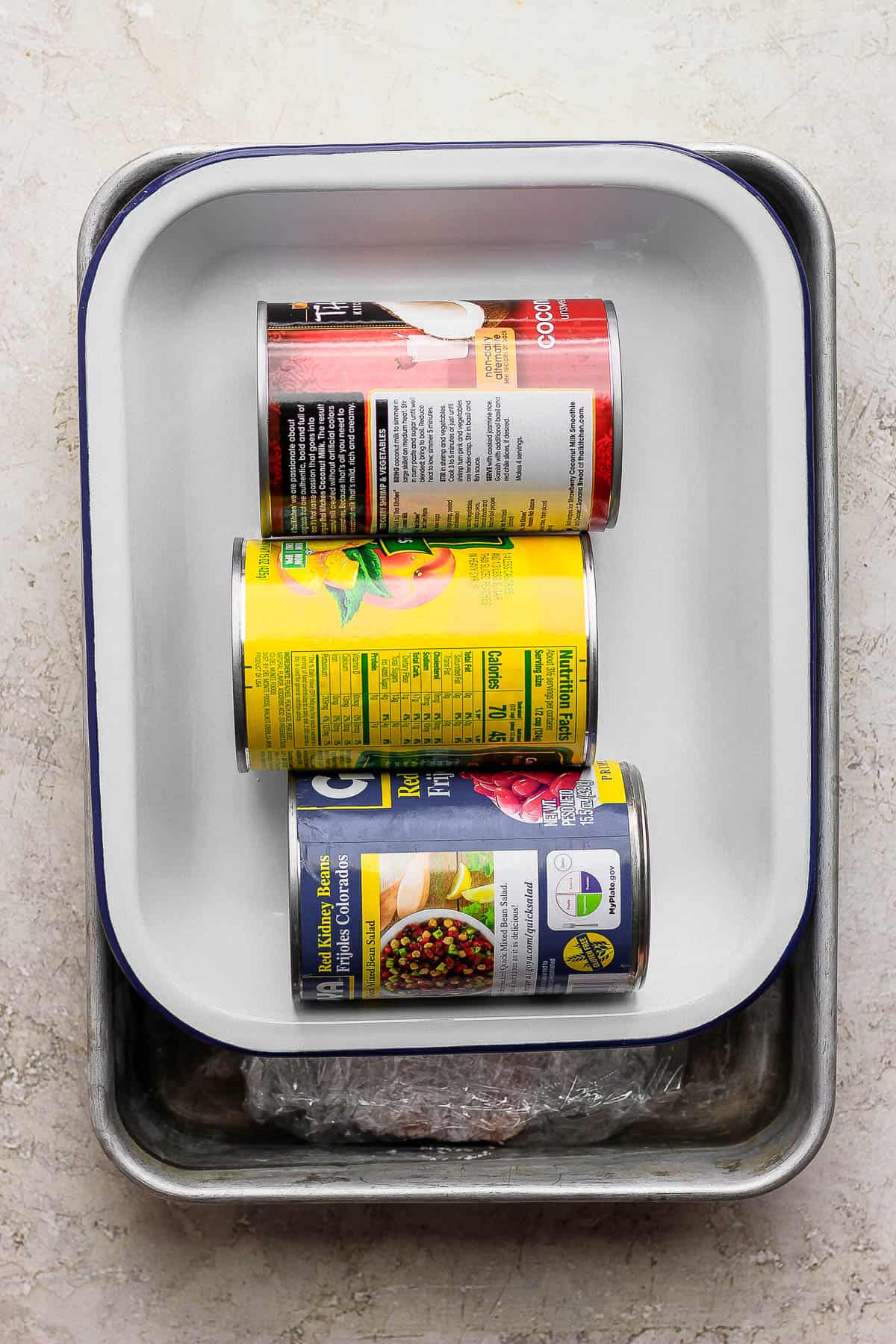 The salmon is prepped for curing with another baking dish on top with three canned good on top to weigh it down. 