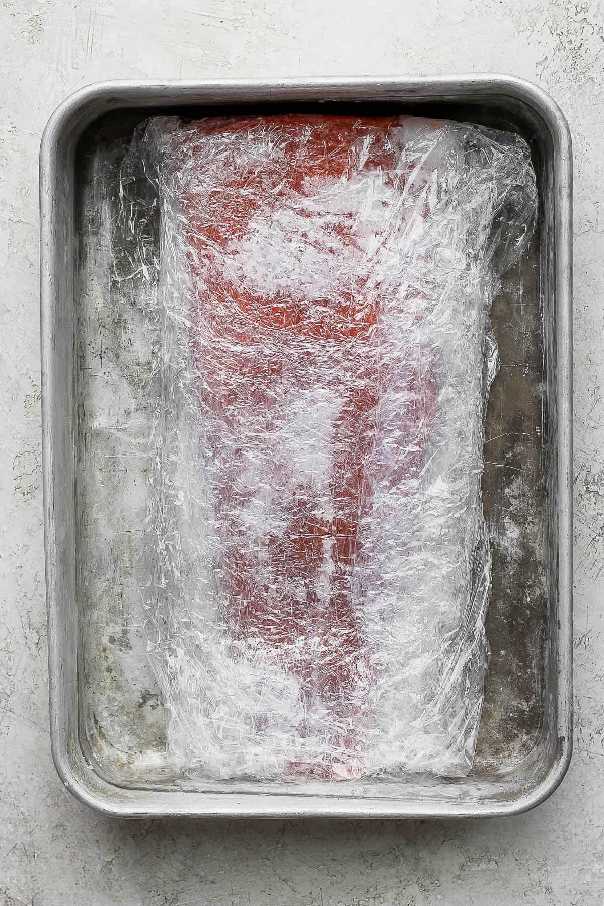 Cured salmon still wrapped in plastic wrap.