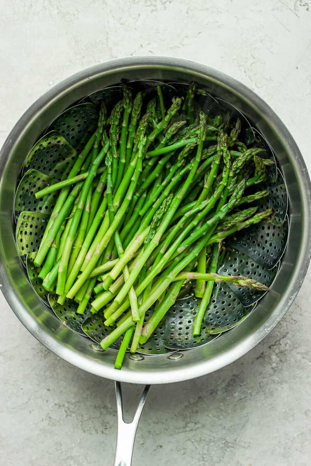 Perfectly steamed asparagus in a steamer basket.