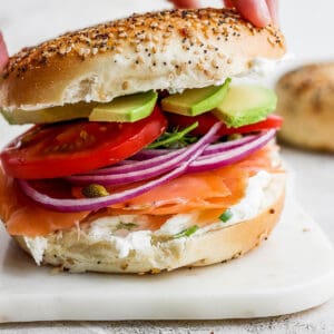 A fully assembled lox bagel on a white marble board.