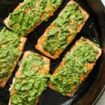 Pesto salmon in a cast iron skillet.