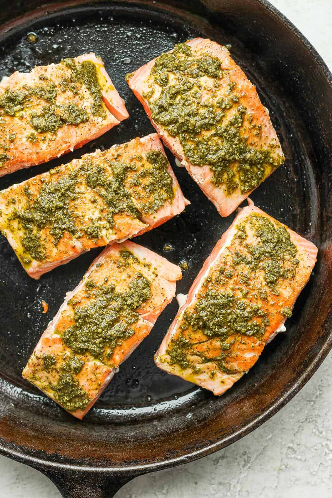 Seared salmon fillets with pesto added on top.