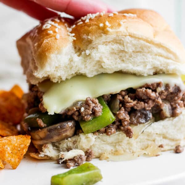 A philly cheesesteak sloppy joe on a plate with chips.