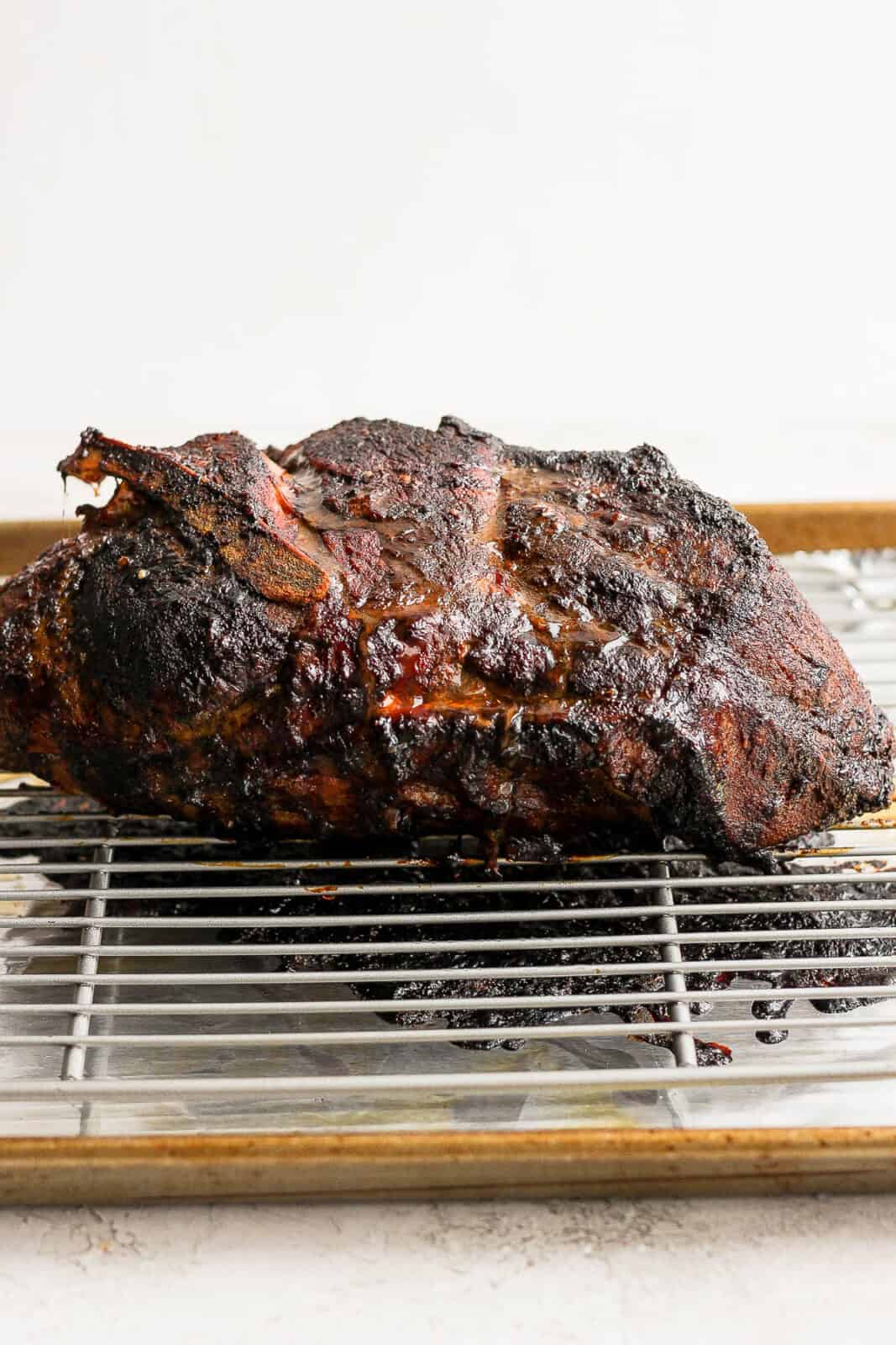 An oven roasted pork shoulder on a wire rack.