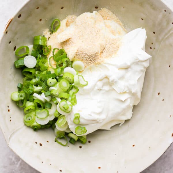 Bowl of scallion cream cheese ingredients in a bowl, but not mixed up yet.