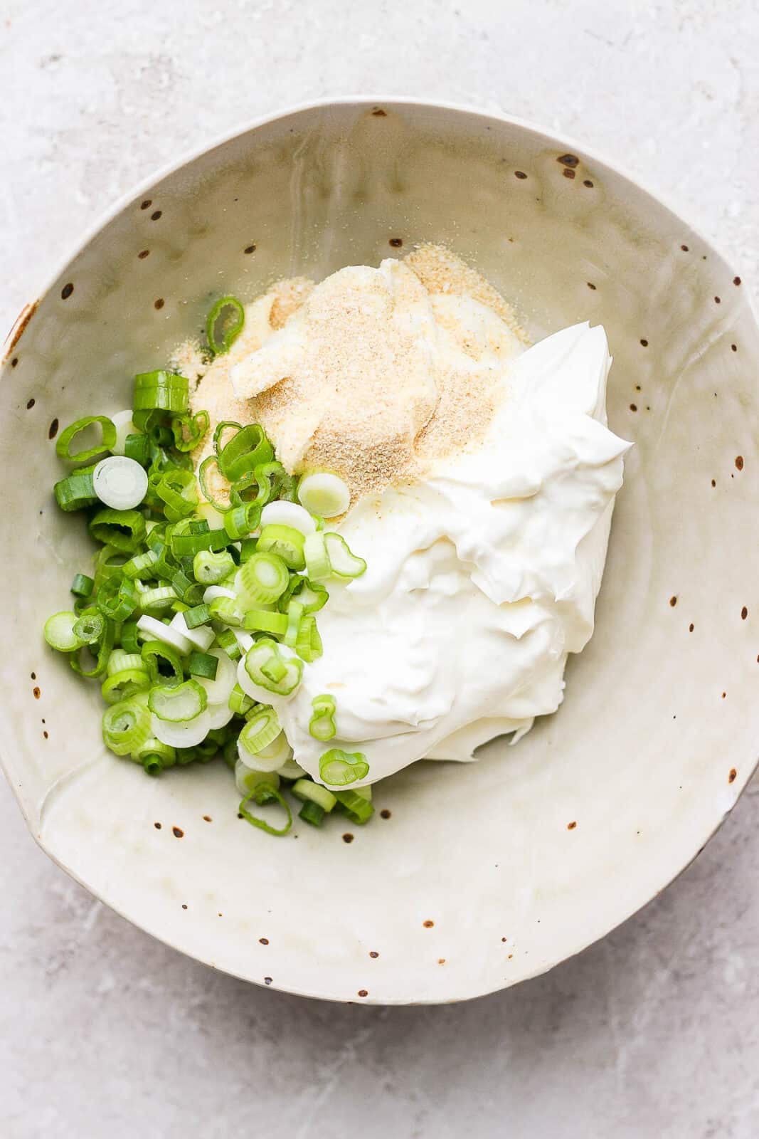 Ingredients for scallion cream cheese spread in a bowl.