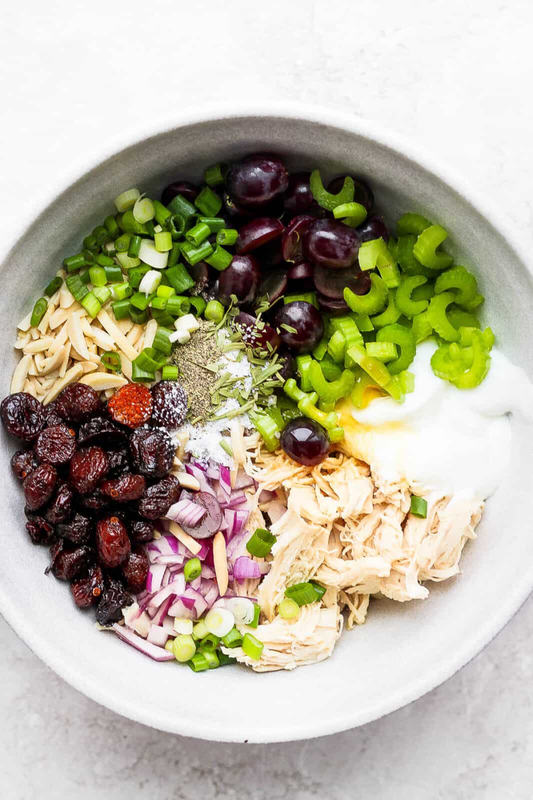 A bowl filed with ingredients for chicken salad. 