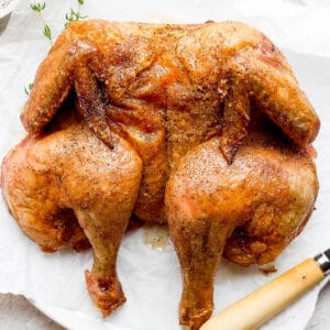 A smoked spatchcock chicken on a plate.