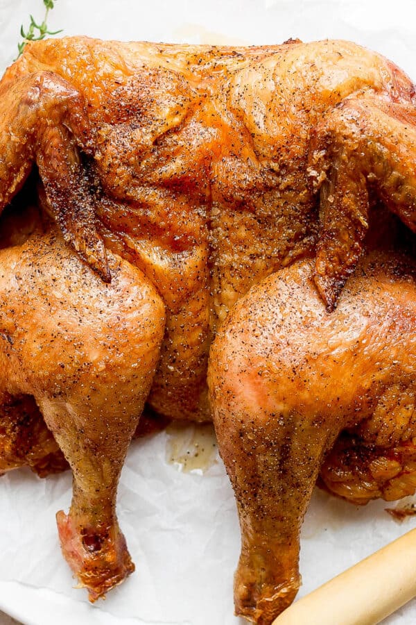 A smoked spatchcock chicken on a plate.