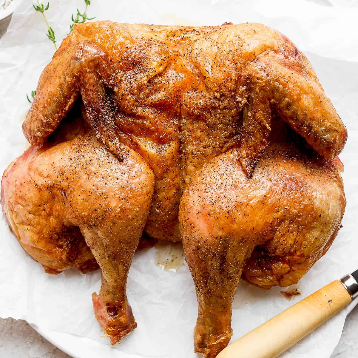 A smoked spatchcock chicken on a plate.