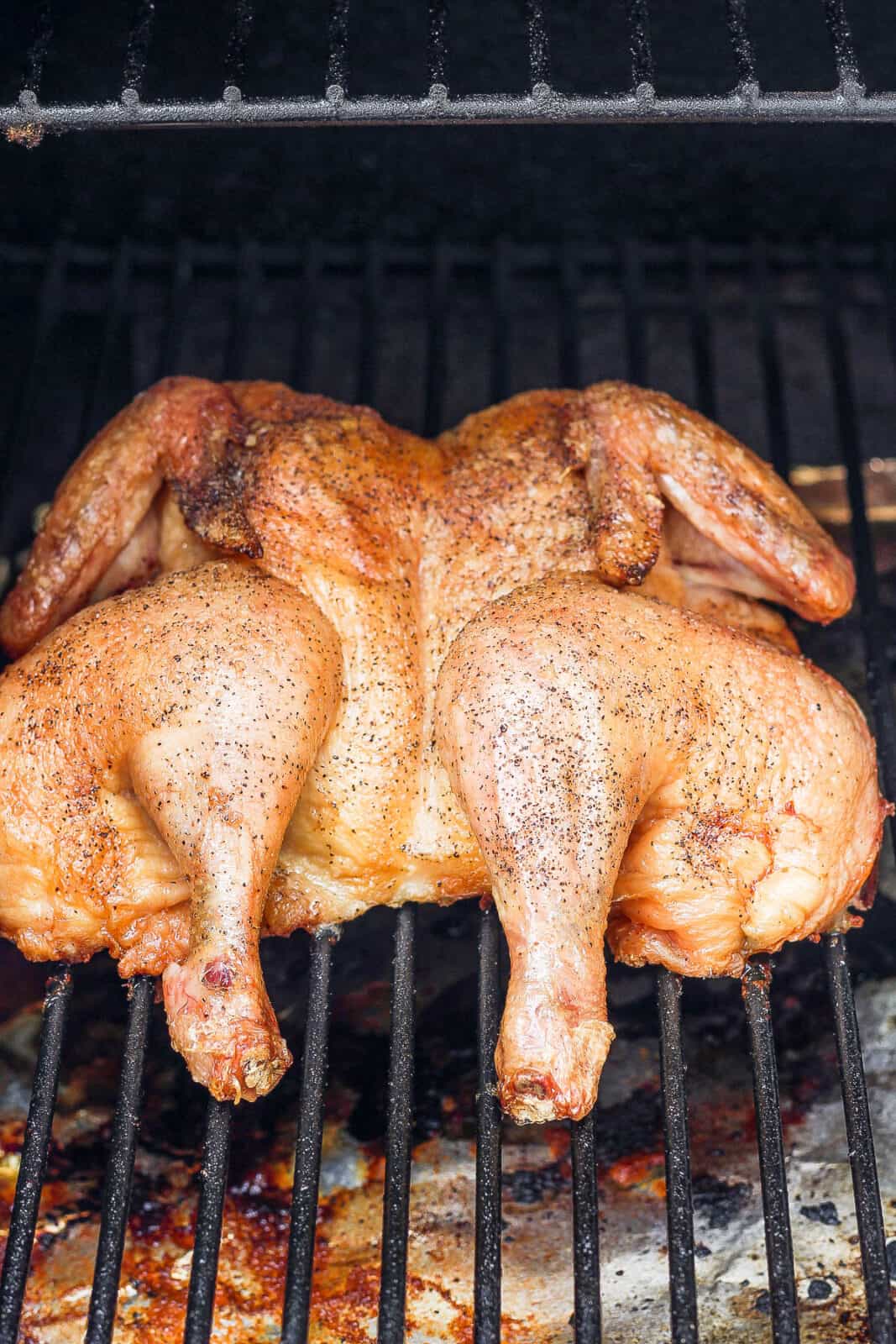 A spatchcocked chicken on the smoker, fully cooked.