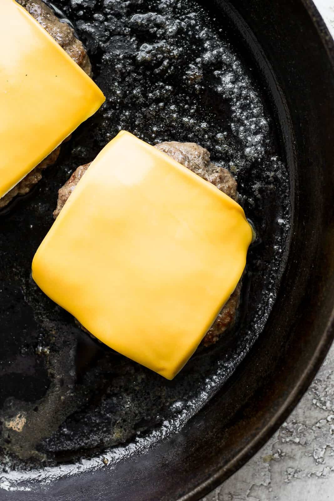 Cheese covering the two burgers.