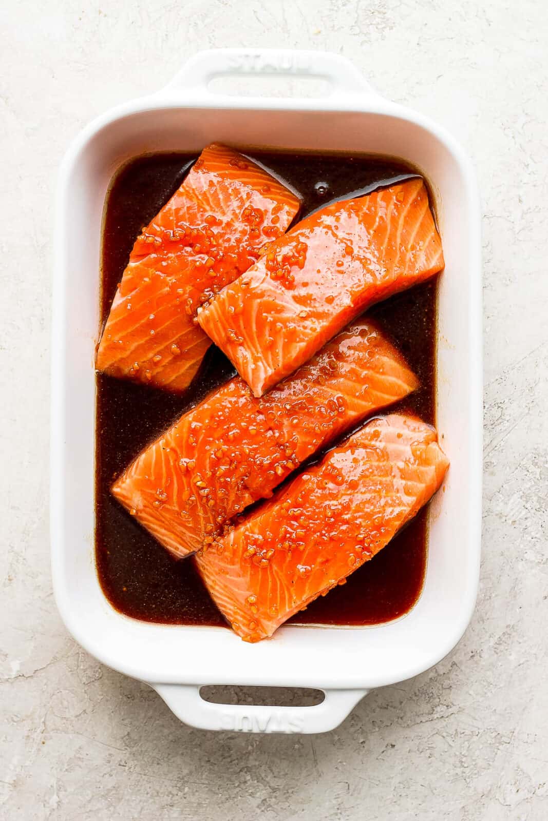 Salmon fillets marinating in a shallow baking dish.