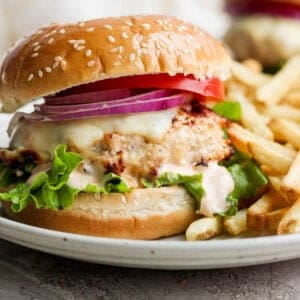 A chicken burger on a plate with fries.