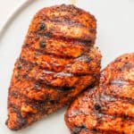 Two grilled chicken breasts with chipotle seasoning on them.