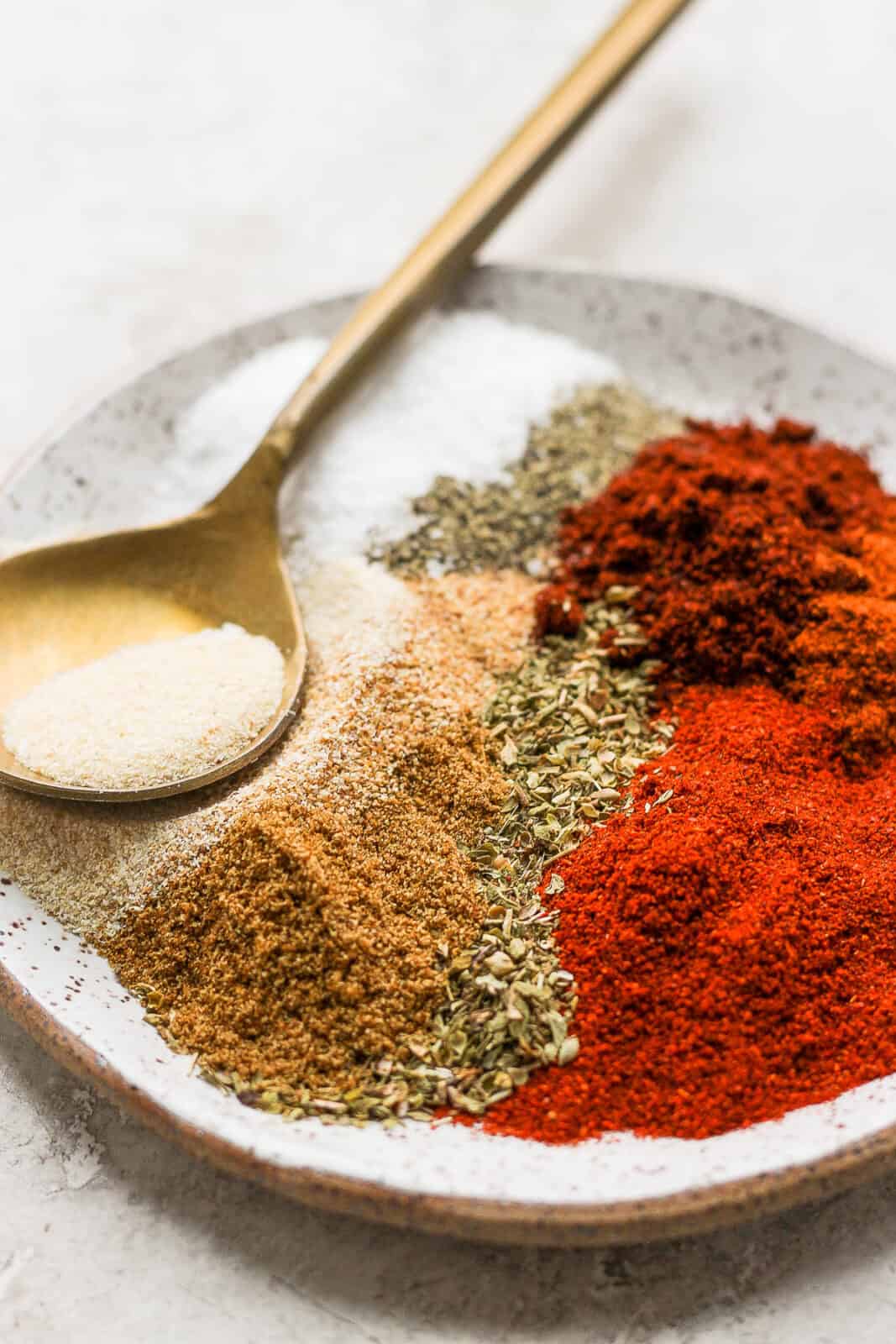 Homemade chipotle seasoning ingredients on a plate with a spoon.