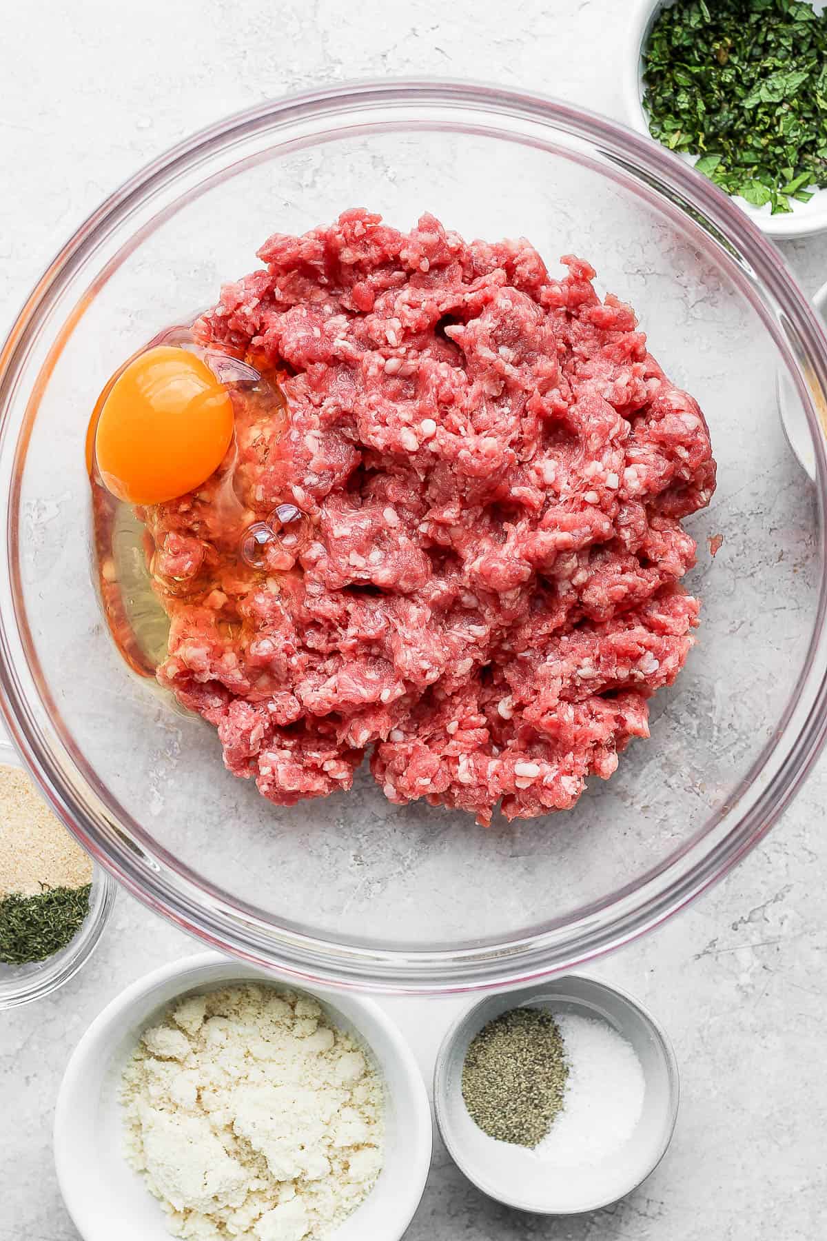 A mixing bowl with ground lamb and an egg.