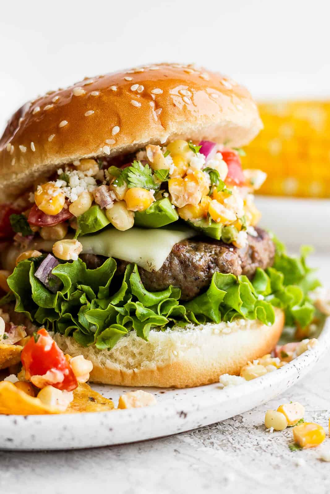 A mexican street corn burger on a plate.