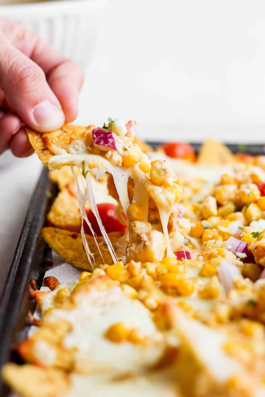 A hand pulling one chip with toppings from the pan.