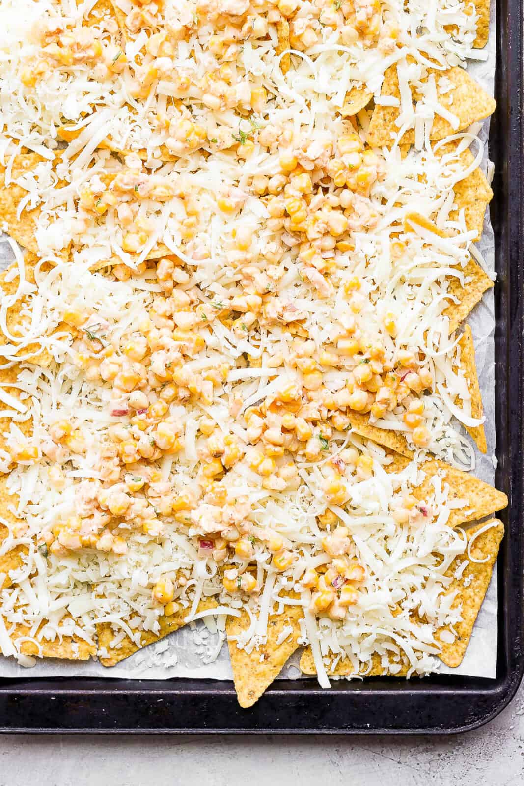 Some mexican street corn salad on top of the first layer of chips and cheese.