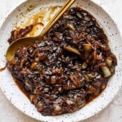 A shallow bowl full of onion jam with a golden spoon sticking out.
