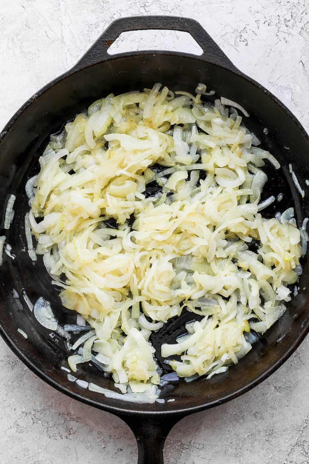 Onion slices beginning to caramelize in the skillet.