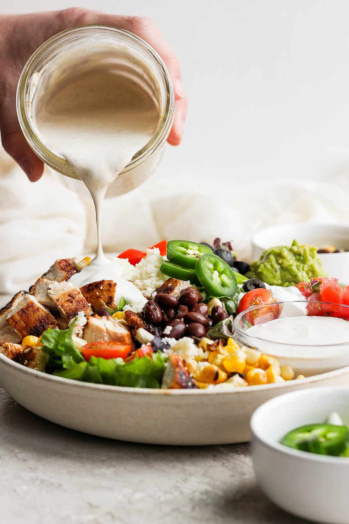 Southwest salad dressing being poured on top of a santa fe salad.