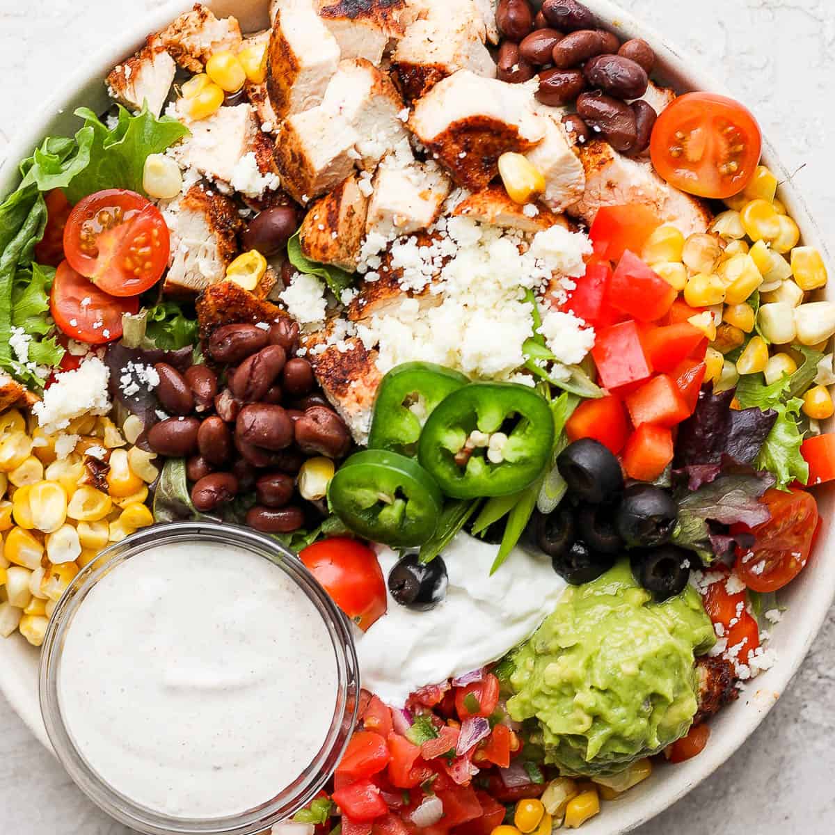 A bowl filled with a santa fe salad and southwest dressing.